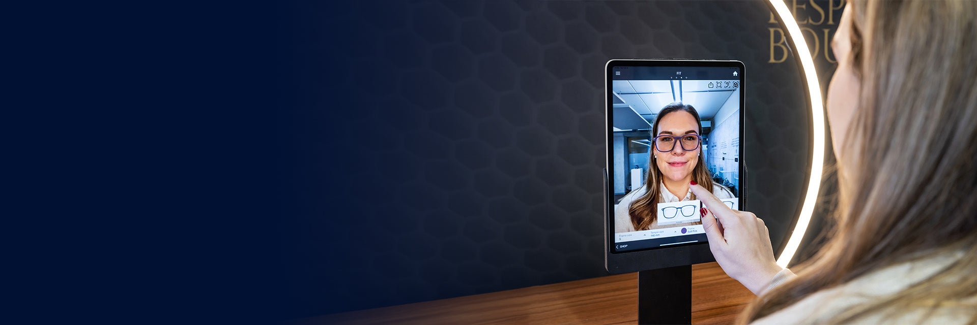 A woman uses the Eyewear Fitting Suite on an iPad. The screen shows her face, along with a generated image of 3D-printed eyewear.