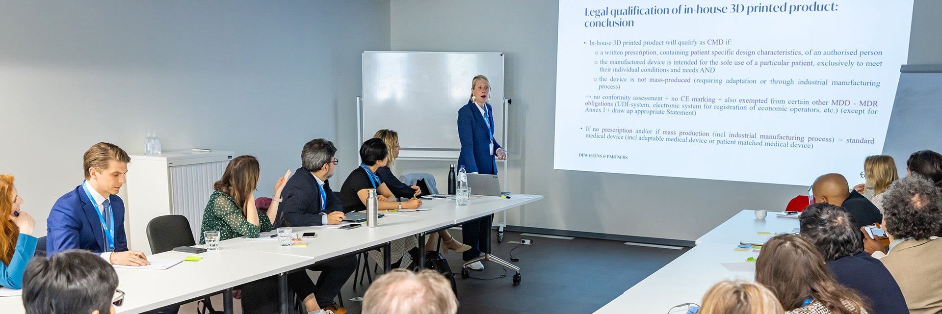 A woman standing in front of a screen presenting to a group of attendees at the Leading Minds Summit