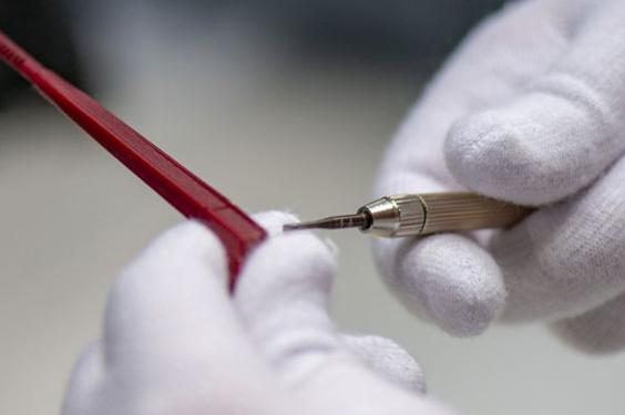Gloved hands holding a tool up to eyeglasses