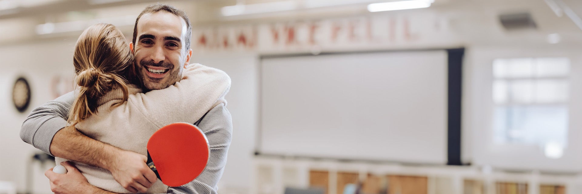 A man and a woman at Materialsie hugging with a ping pong paddle in hand