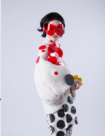 Modelo con un traje blanco con círculos rojos y negros y gafas de sol rojas diseñado por David Ring