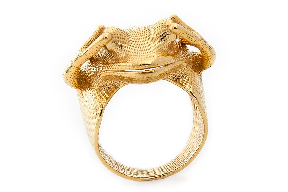 A gold ring in the shape of a frog with its hands over its eyes made with lost-wax casting.