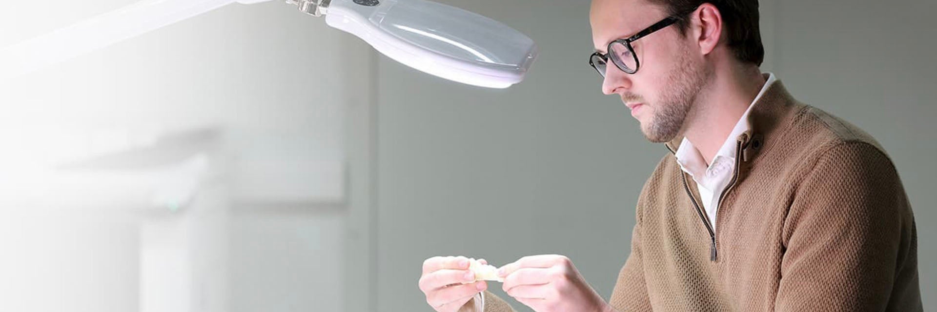 Man looking at a 3D-printed part under a light