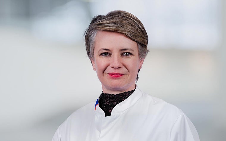 Dr. Joanna Wykrzykowska standing against a pale, blurred out background