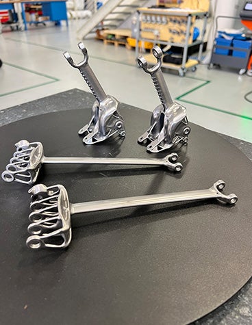 A close up of four metal 3D-printed parts that make up the catamaran's pulley system 