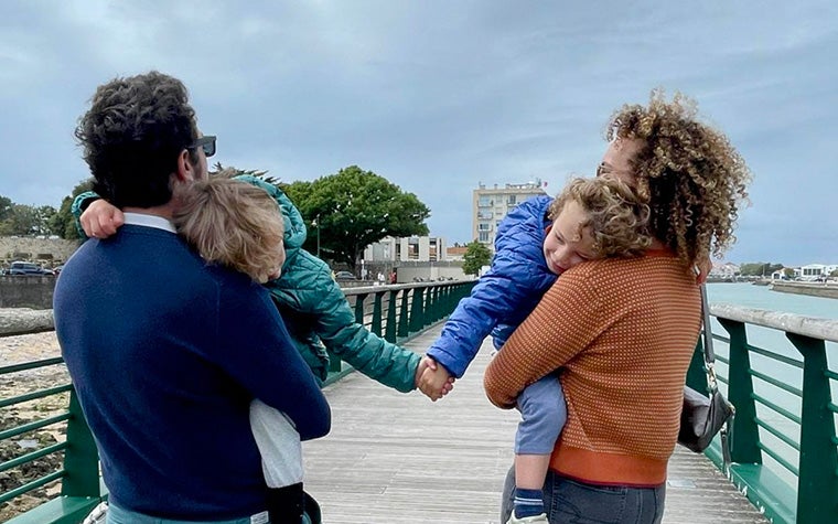 A woman (Nora Toure) is standing with her husband and two sons and looking toward the horizon. Her two sons are holding hands.