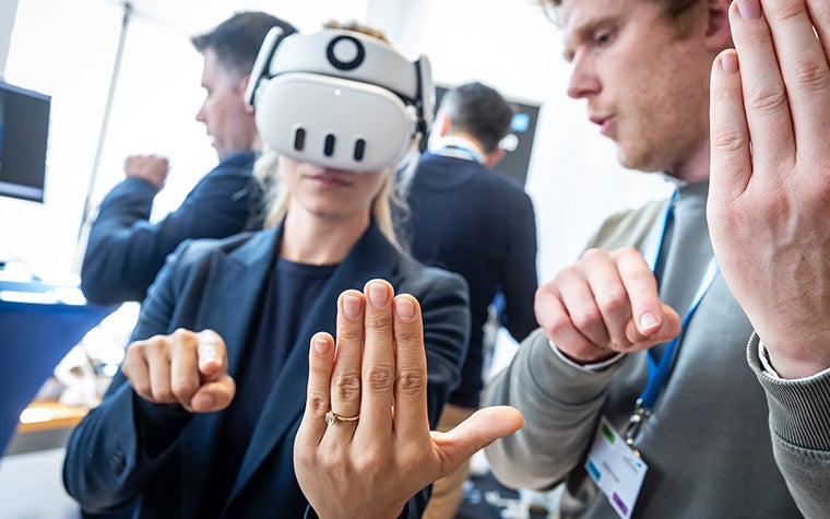 A woman testing out the Meta Quest 3 augmented reality goggles for healthcare applications with the support of a Materialise expert at the 3D Planning and Printing in Hospitals Forum 2025