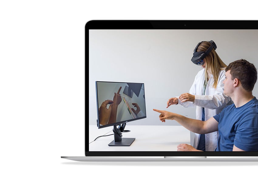 A doctor wears googles to view patient anatomy in AR while an engineer watches on a computer screen