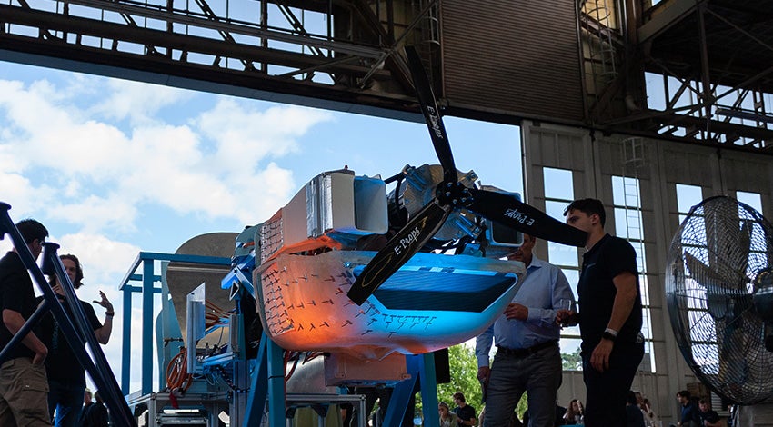 A group of students from TU Delft standing in an aircraft hangar next to a partially disassembled Sling 4 kit aircraft that they have retrofitted with a liquid hydrogen engine.