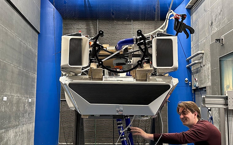 A TU Delft student stands next AeroDelft's 3D-printed air ducts for a Sling 4 kit aircraft retrofitted with a liquid hydrogen engine inside a wind tunnel.