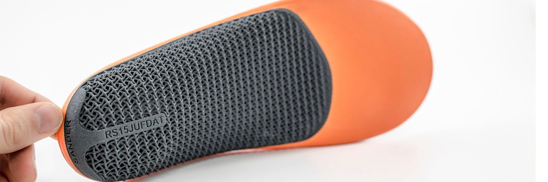 Fingers holding up a 3D-printed, personalized insole