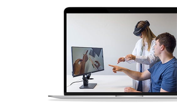 A doctor wears googles to view patient anatomy in AR while an engineer watches on a computer screen