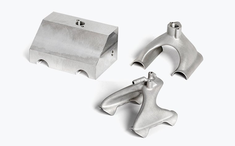 Side-by-side comparison of a suction gripper to be used on production lines. One on the left is bulkier and created with conventional manufacturing methods, and the ones in the center and on the right are sleek and made with 3D printing.
