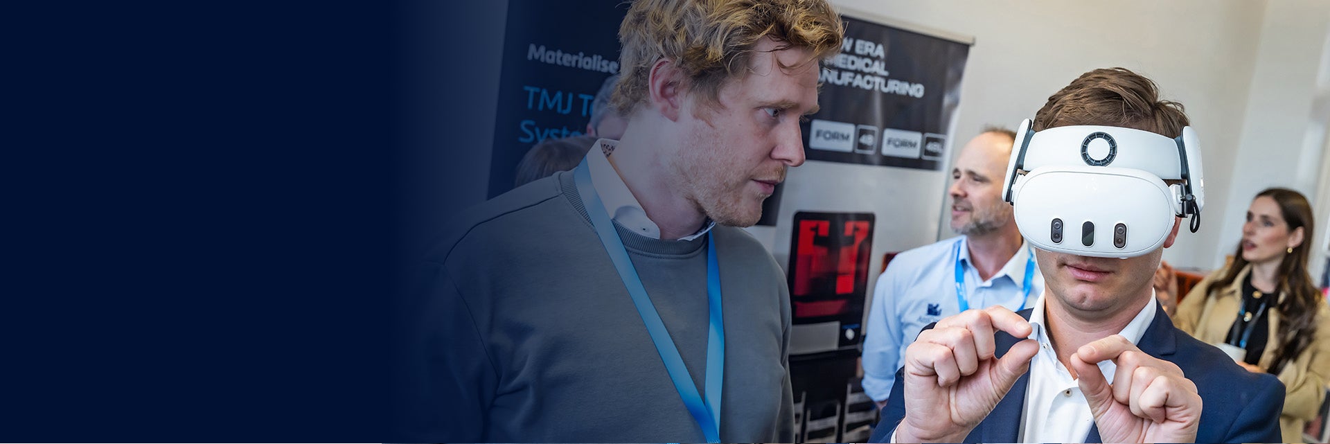 A man watching another man wearing an augmented reality headset. The wearer is holding both hands up in a pinching position