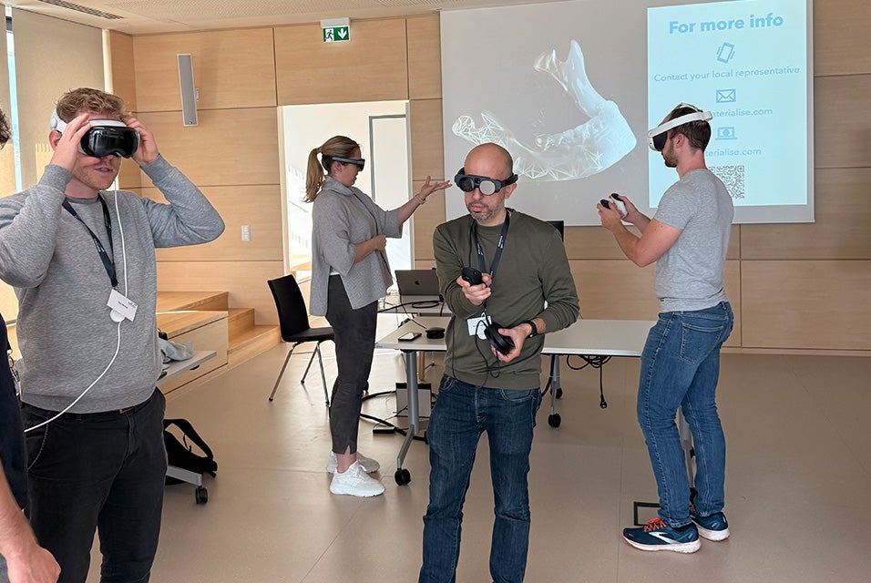Materialise CMF Wet Lab participants using virtual and augmented reality headsets, with a presentation screen displayed in the background.