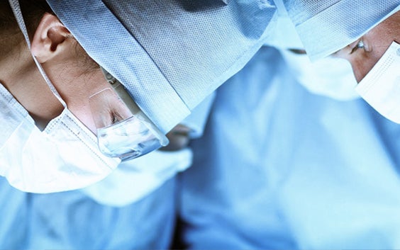 A group of surgeons in surgical gear, looking down