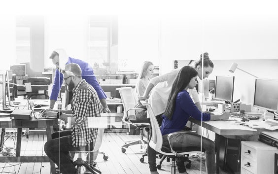 Group of people in an office environment using computers and talking