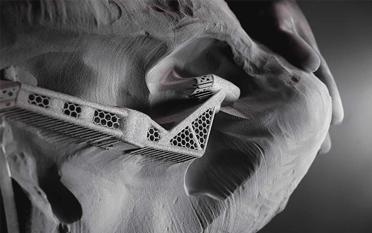 A Zenith Tecnica employee taking a 3D-printed part out of the powder bed.