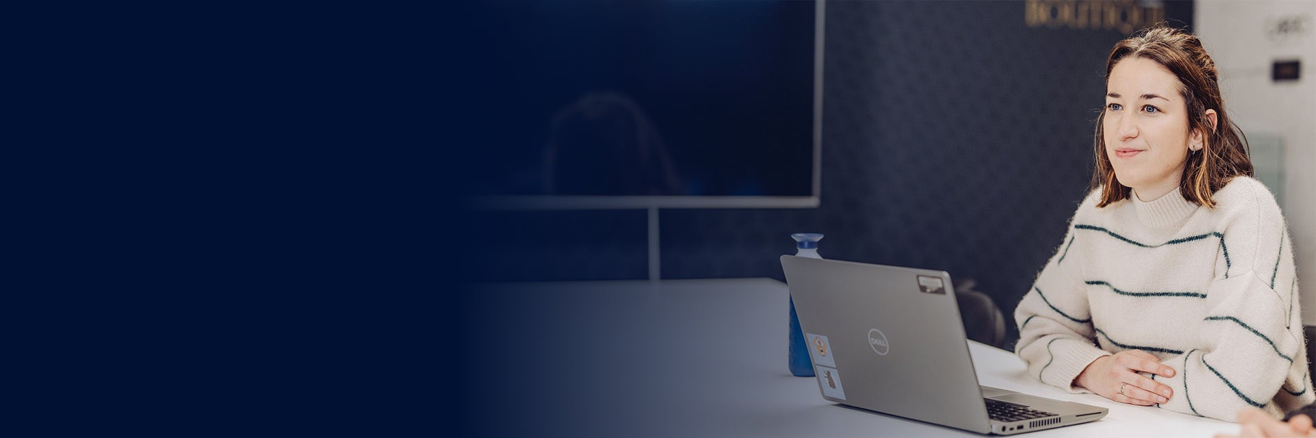 Woman smiling while sitting at a computer with her arms crossed on a desk
