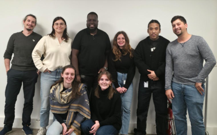 A large group of Materialise employees standing against a white wall in a Materialise office in France