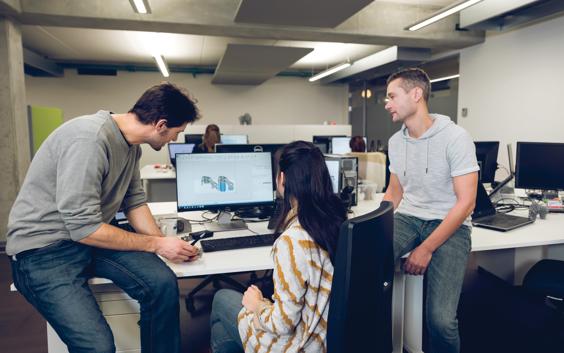 Software application engineers gathered around a computer, reviewing the Magics software