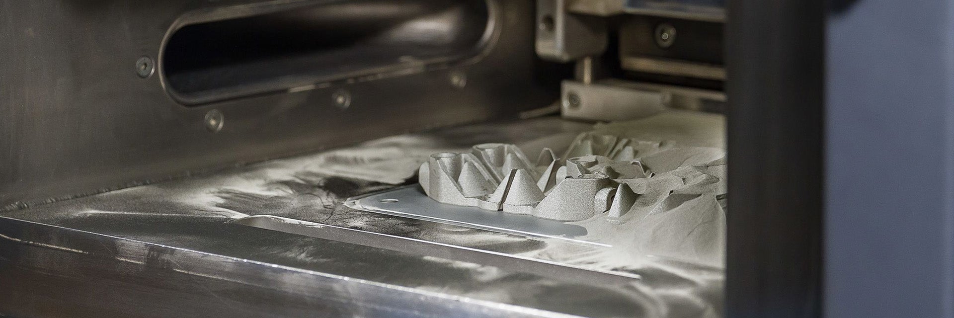 A series of 3D-printed parts being formed in a powder bed.