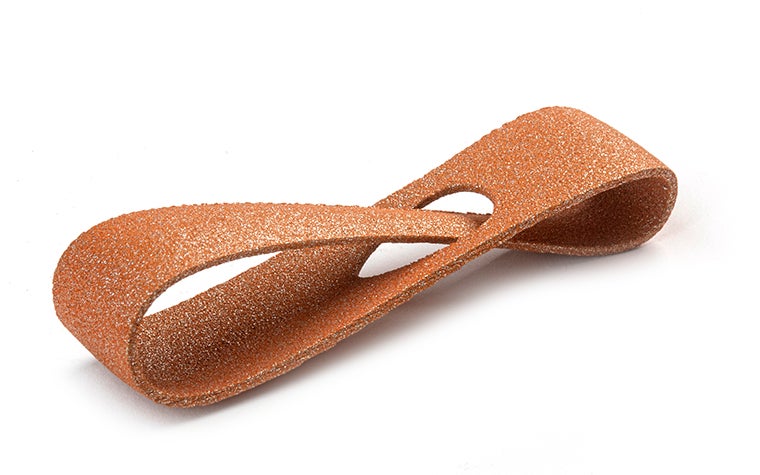 Une boucle orange scintillante imprimée en 3D, réalisée en PA-AF (aluminium chargé) par frittage laser, avec une finition teintée dans la masse.