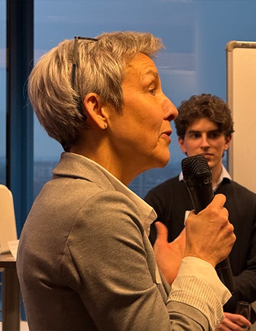 Materialise CEO Brigitte de Vet speaking into a microphone at the opening of Materialise's Aerospace Competence Center