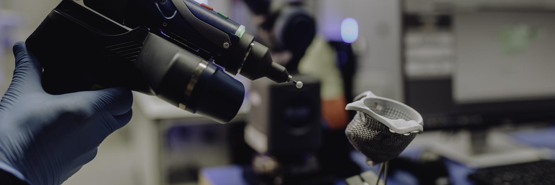 Main gantée utilisant un outil pour scanner optiquement un implant médical en vue d'une évaluation de qualité