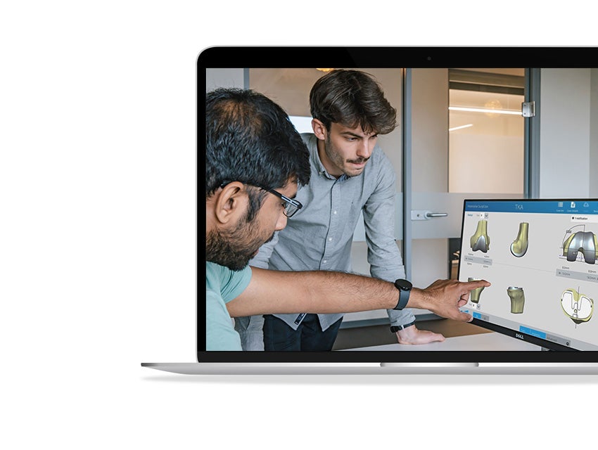 Two men looking at a computer screen with SurgiCase open to bone models.