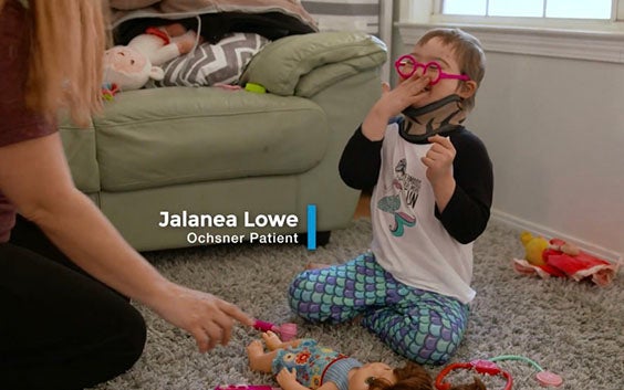 5-year-old Jalanea Lowe sitting on a carpeted floor, surrounded by toys and facing a woman