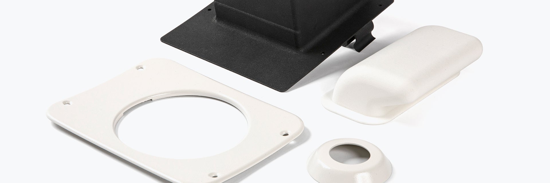 Four 3D-printed spare parts made of flame-retardant polyamide are shown: one is black and three are white. All four parts are commonly seen in aircraft cabin interiors. These parts are manufactured for 328 Support Services.