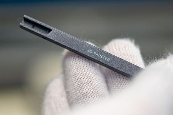 Gloved hand holding a piece of eyewear that says 3D printed