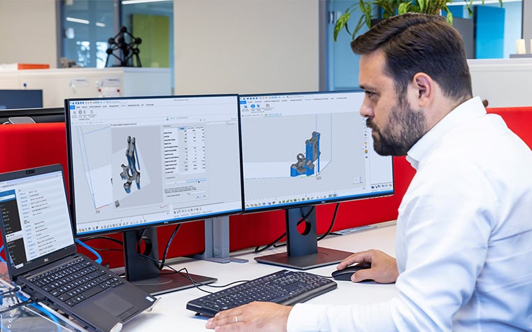 A man looking at two monitors and a laptop screen with the Magics SDK software displayed. 