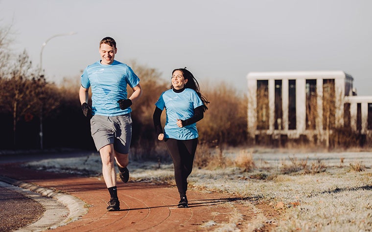 A man and woman running on a path in winter