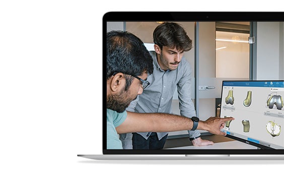 Two men looking at a computer screen with SurgiCase open to bone models.