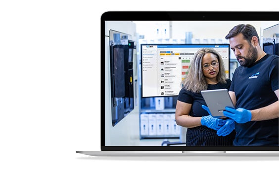 Two Materialise employees discuss a project on a small tablet.