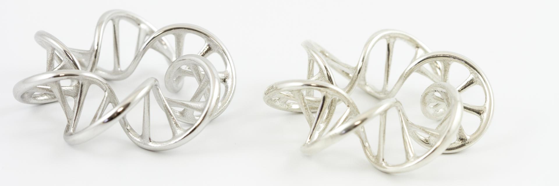 Two 3D-printed pendants in silver shaped like DNA strands