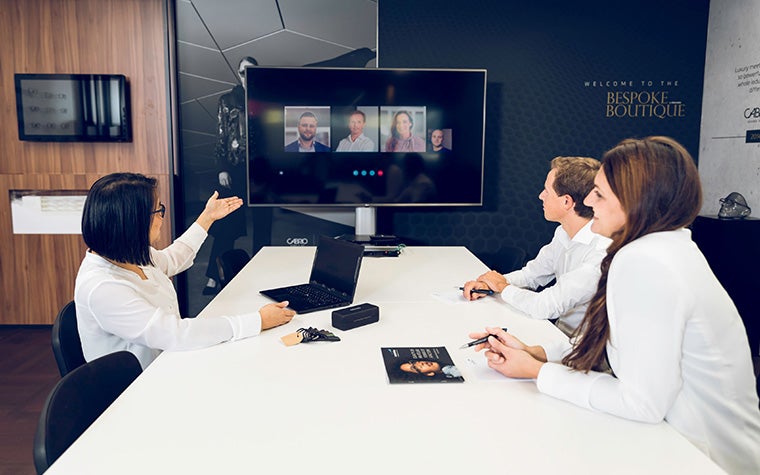 A hybrid work meeting with a group in a room talking to colleagues on a conference call