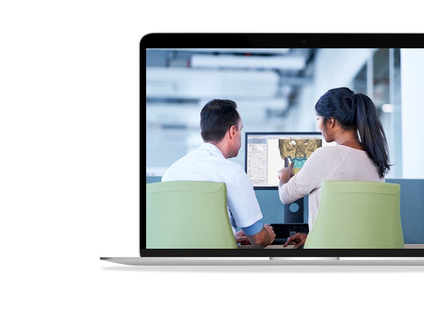 A man and a woman looking at a computer screen to plan for CMF preoperative planning.