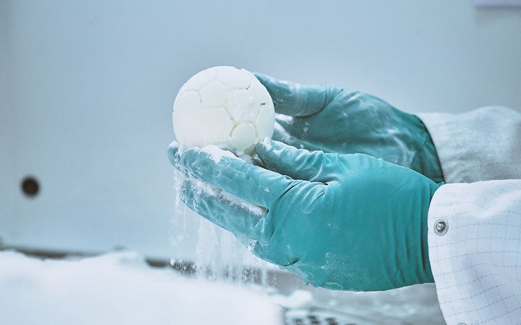 手袋をはめた手で3Dプリントのボールを持ち、そこから3Dプリントの粉が落ちる