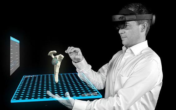 Microsoft 홀로렌즈를 착용한 남성이 Mimics Viewer의 증강 현실 기능을 사용하여 고관절 및 엉덩이 임플란트 모델을 검사하고 있습니다.