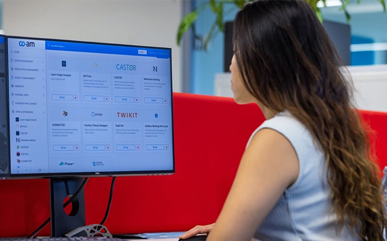 Woman sitting at a desk and looking at CO-AM on her computer screen