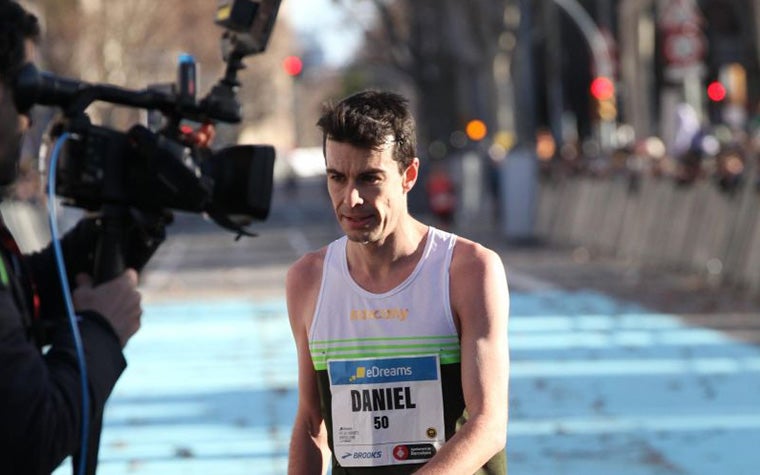 Distance runner Dan Studley completes the Barcelona half-marathon. A cameraman films him as he crosses the line.