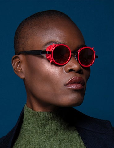 Gros plan d'un modèle féminin noir regardant hors caméra et portant des lunettes de soleil rouges de la collection ReyStudio NAUTINEW