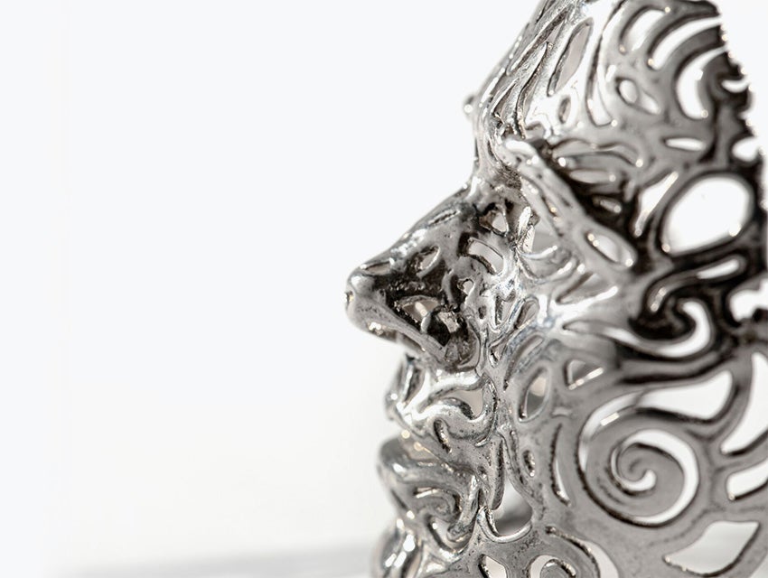 A profile image of an intricate silver face mask made with lost-wax casting.