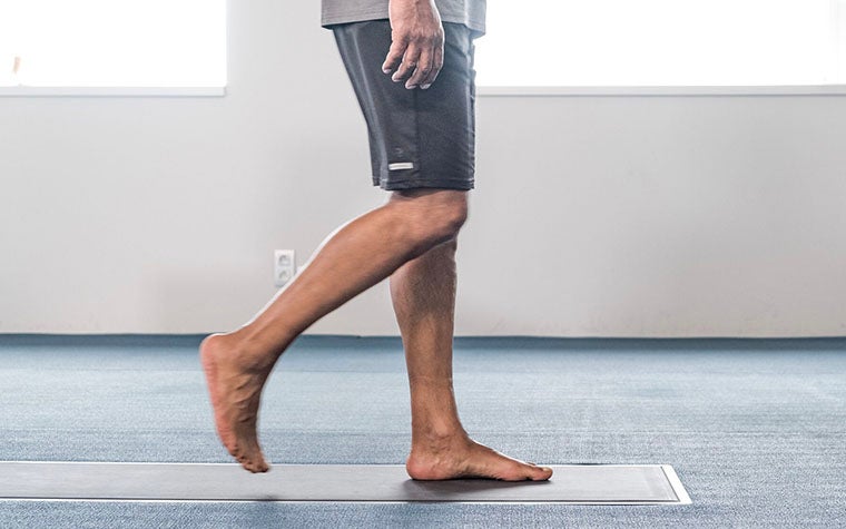 A man in shorts walks barefoot over a footscan pressure plate.