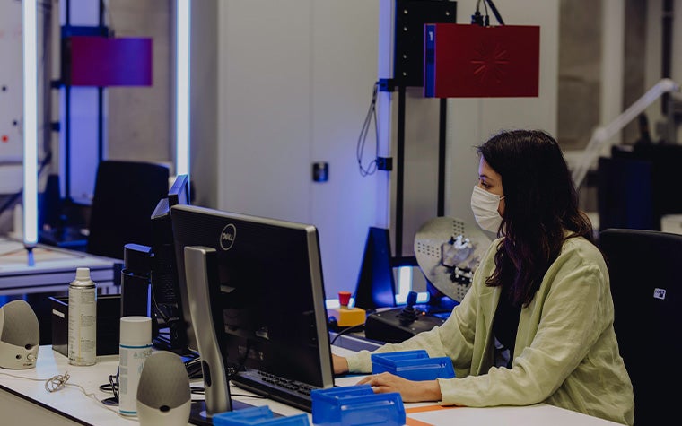 A woman with a face mask on working at a desktop computer