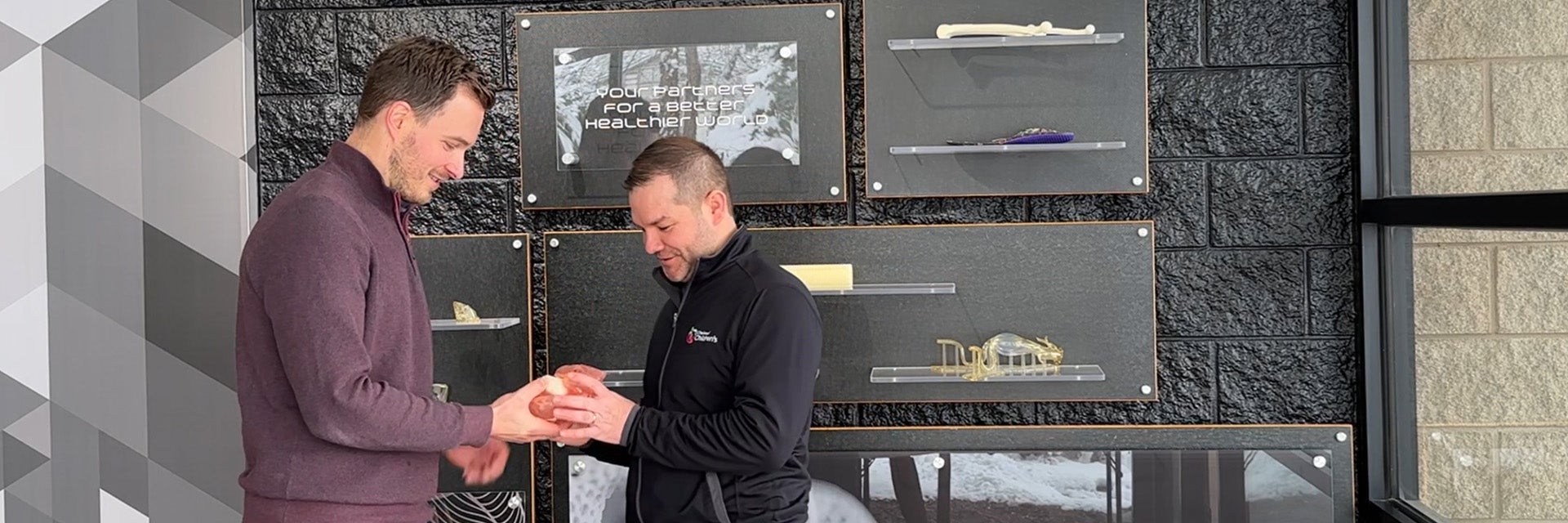 Dr. Ryan Moore looking at a 3D-printed heart model in the Materialise office with a colleague from Materialise