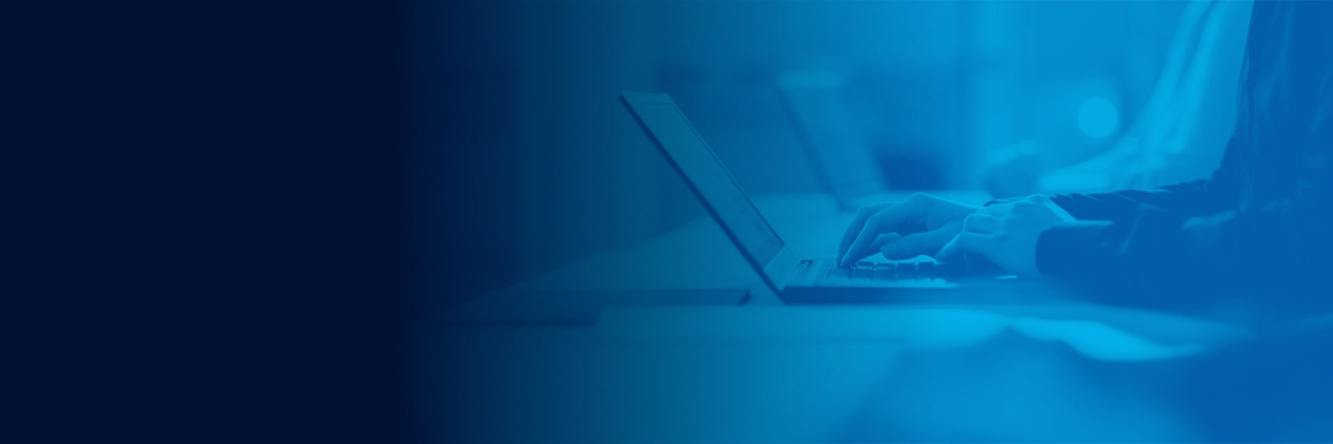 A person typing on a laptop with a blue filter over the image.